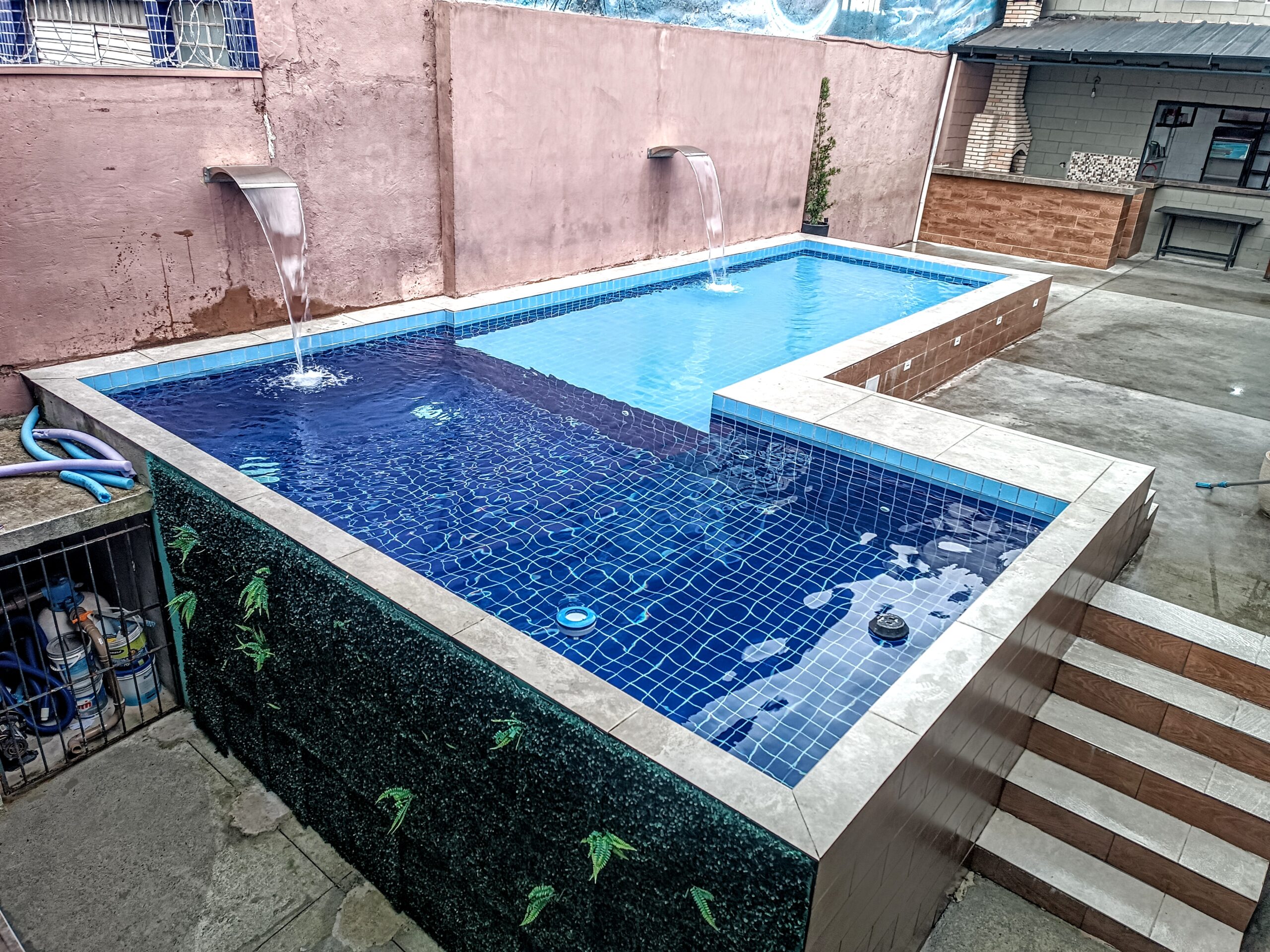 Técnico realizando tratamento de piscina de alto padrão com água cristalina. Serviço especializado de análise química, balanceamento da água, aspiração, escovação e uso de produtos adequados para garantir limpeza, segurança e economia na manutenção da piscina.